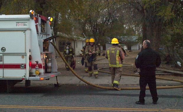 Susanville Police Chief Tom Downing watches as fire fighters make entrance to a house on Russell Avenue Friday afternoon.
